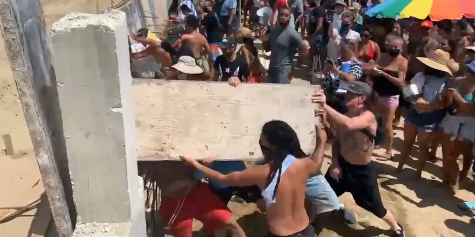 People busting down a fence.