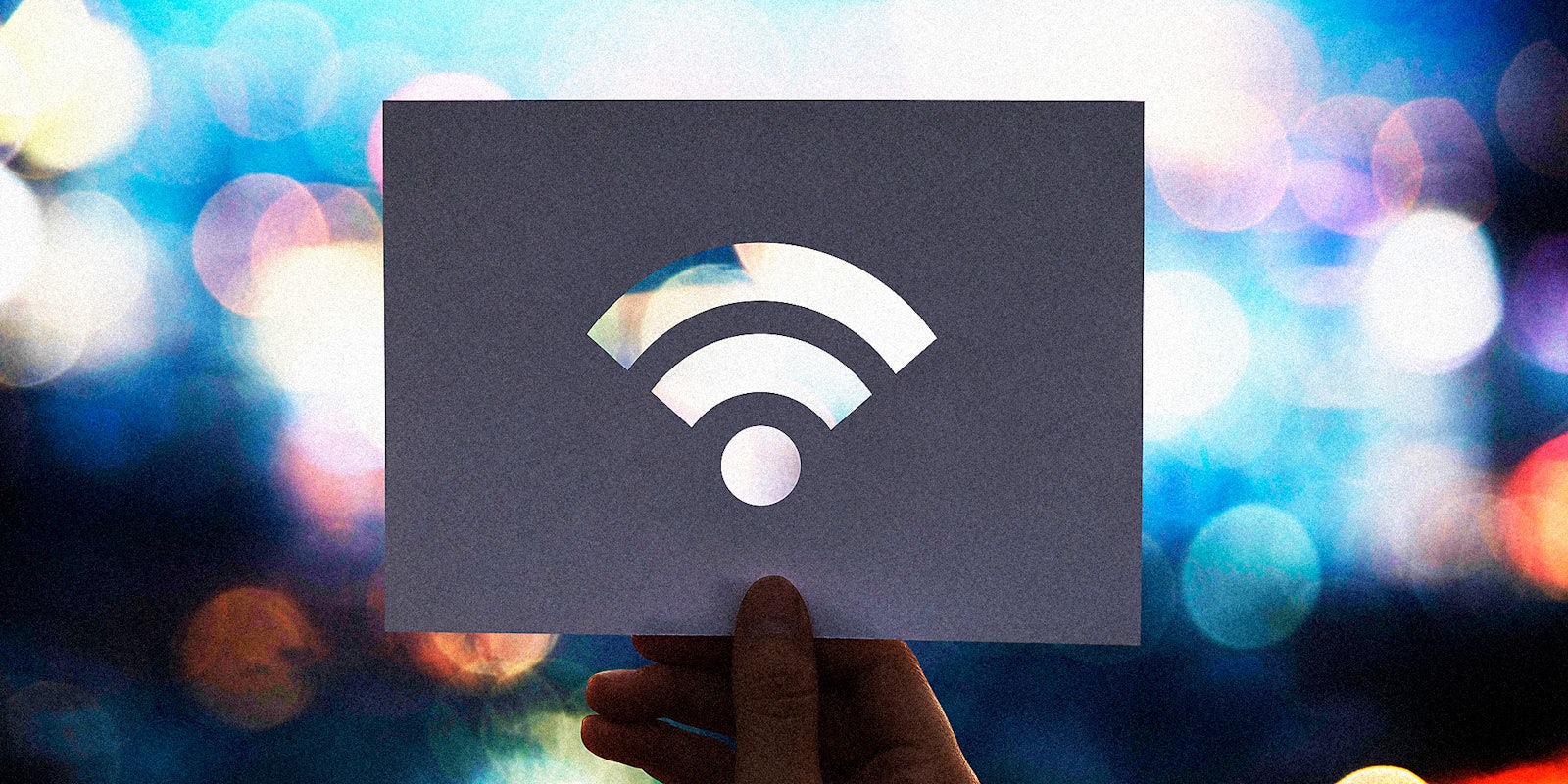 A hand holding a piece of paper with a Wi-Fi signal on it. It is meant to try and represent municipal broadband.
