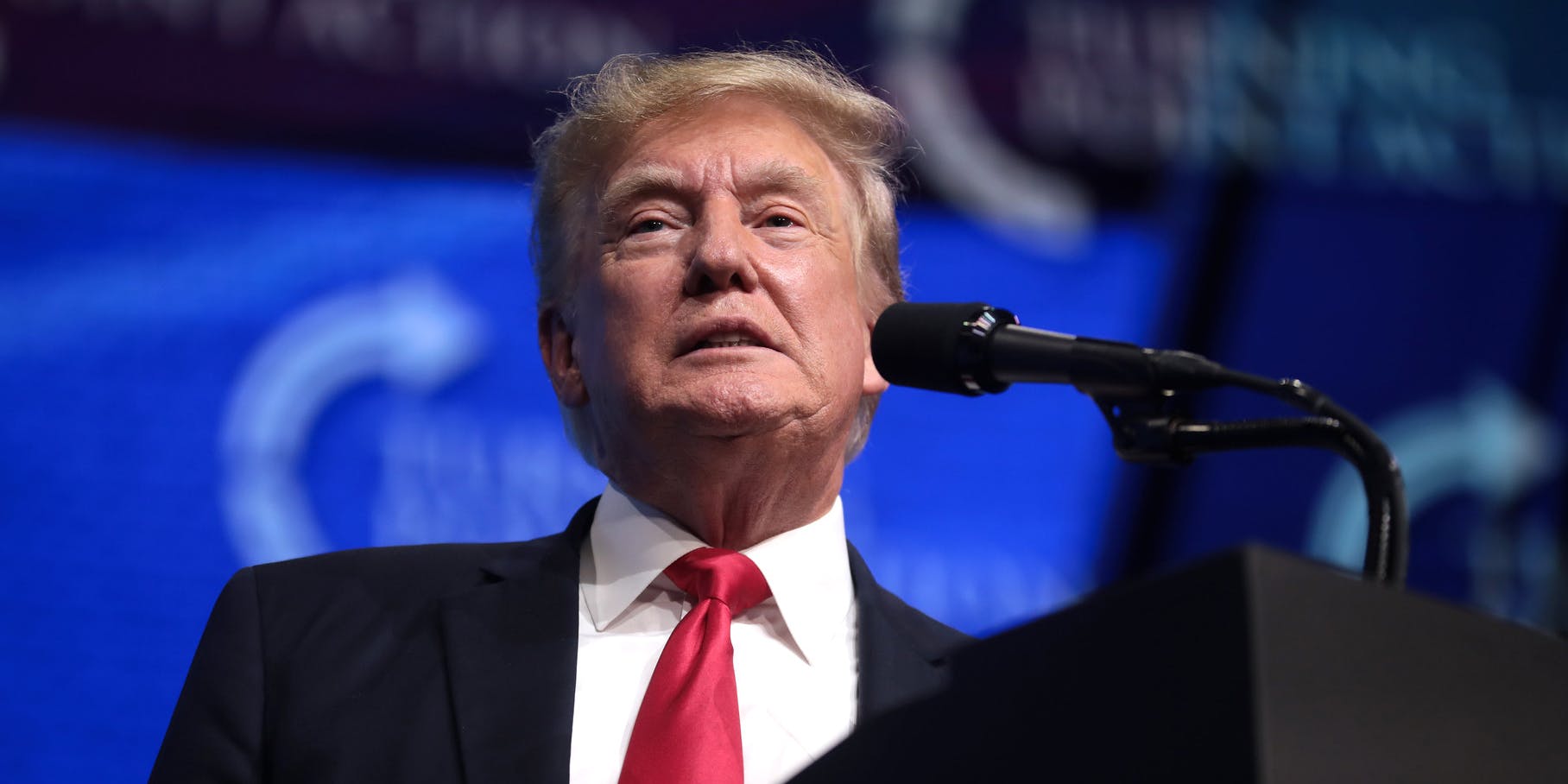 Former President Donald Trump speaking in front of a microphone.