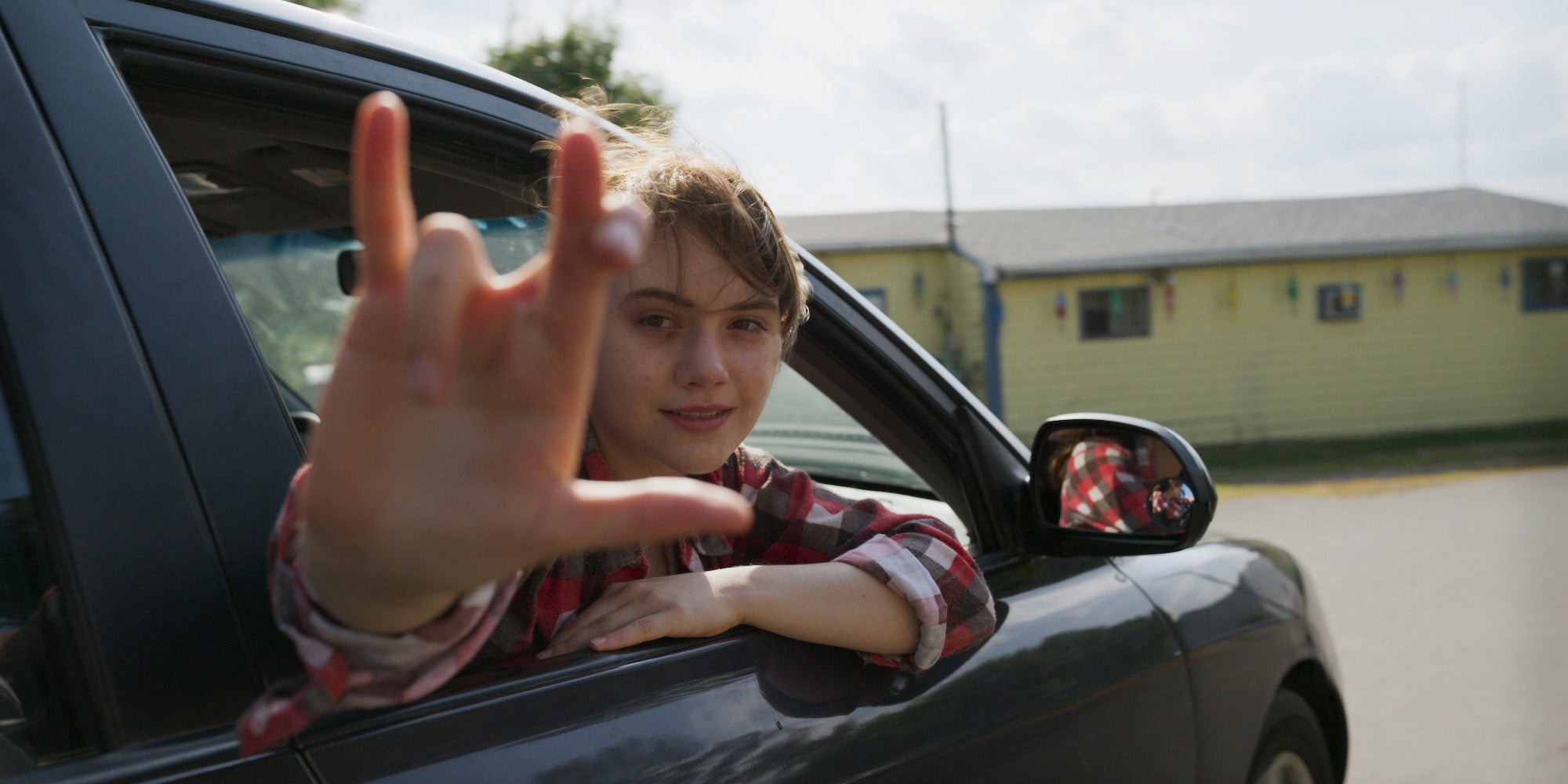 teen girl making i love you sign in car