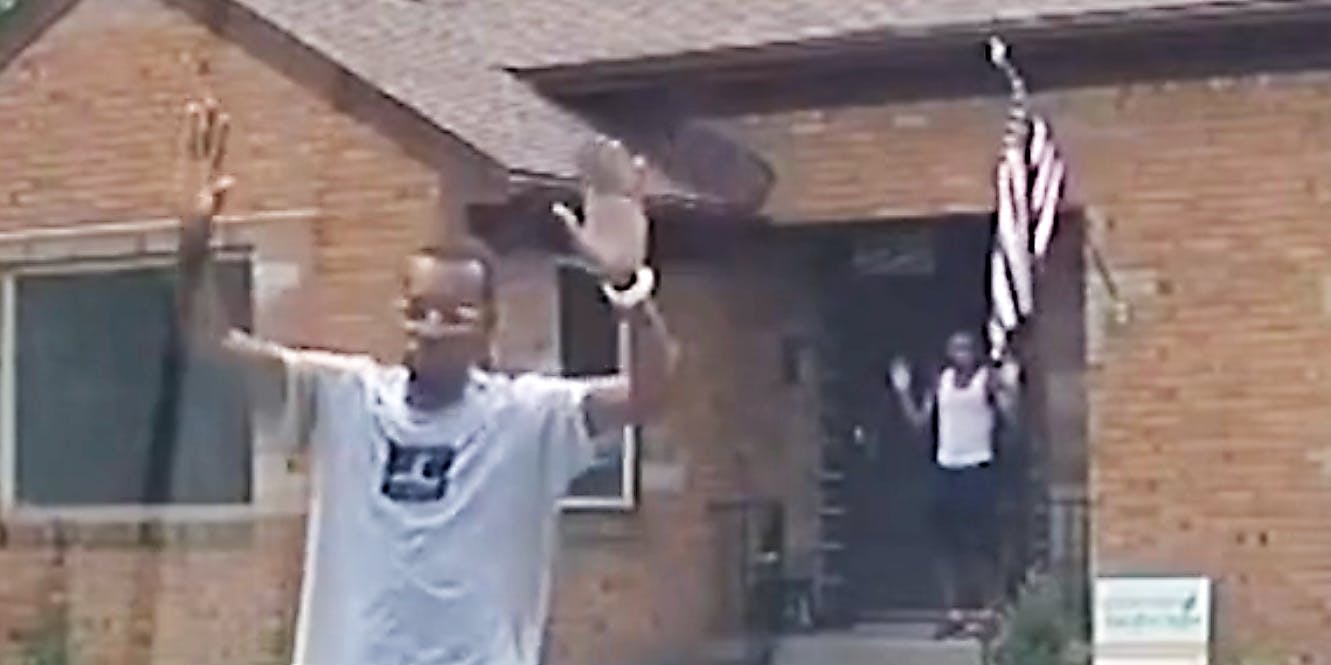 Two black men with their hands in the air.