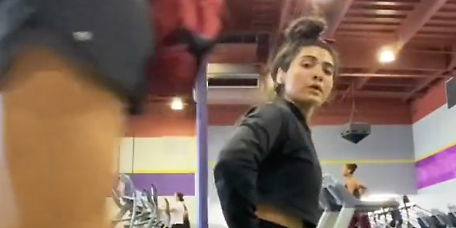 A woman walking past another woman in a gym.