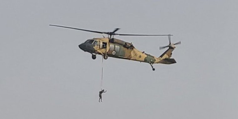 a human figure suspended under a helicopter