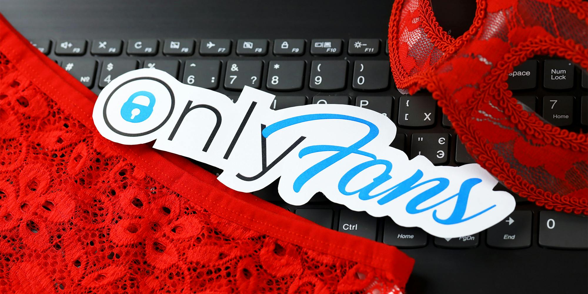 Onlyfans paper logo and red lingerie on black laptop keyboard
