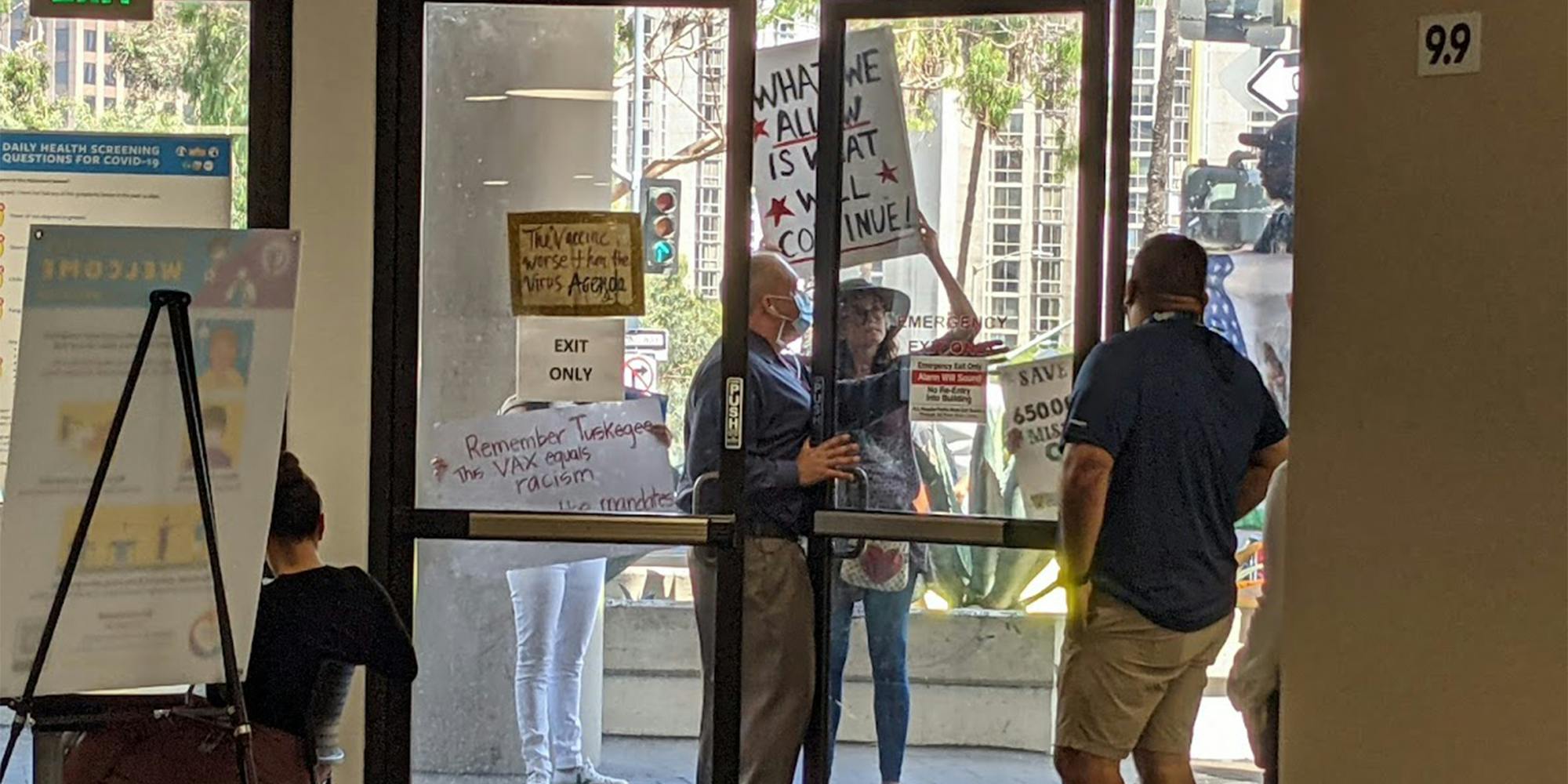 anti-vax protesters outside of glass doors