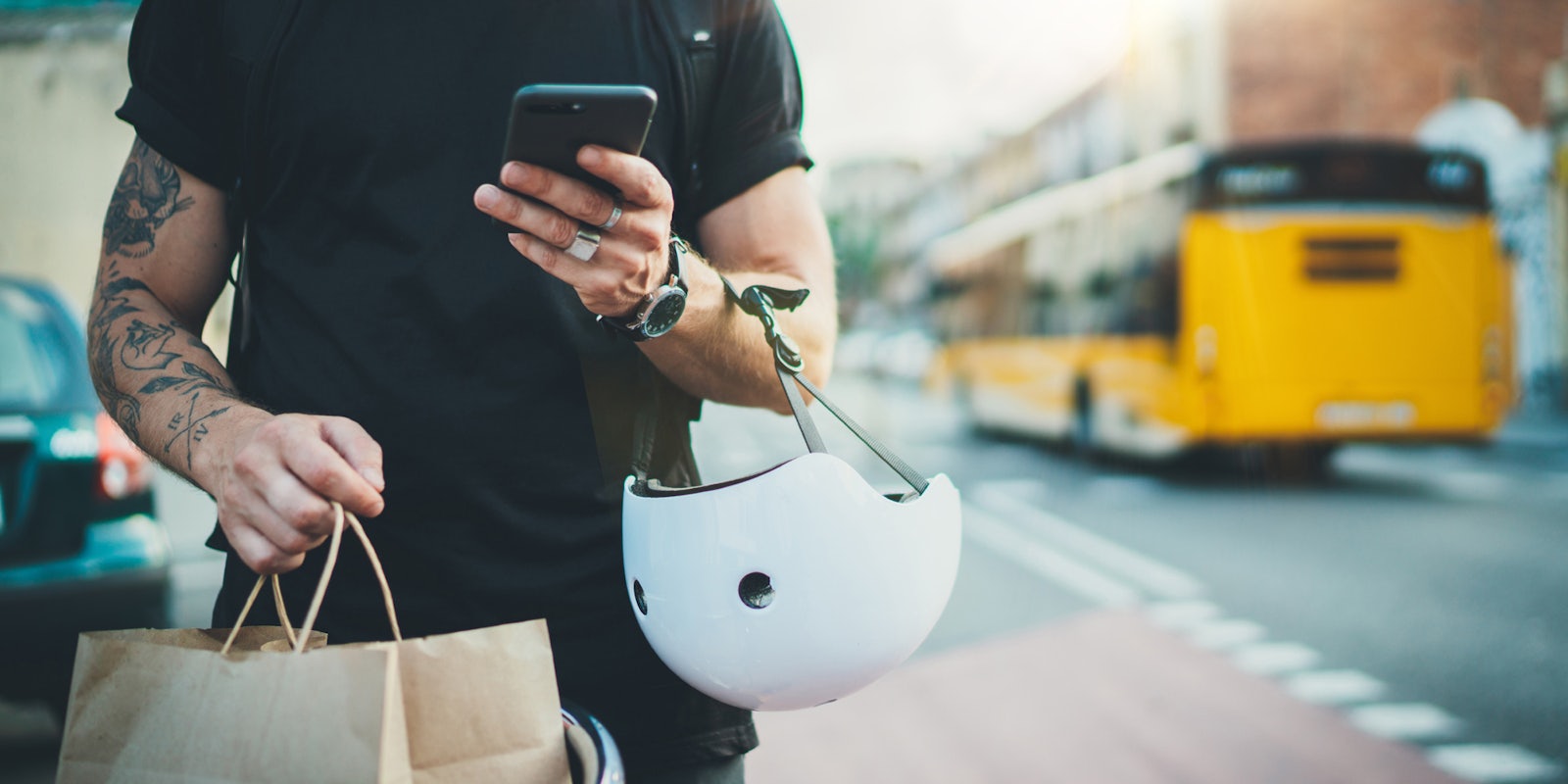 A man using a delivery or rideshare app. He is holding a bag and a helment.