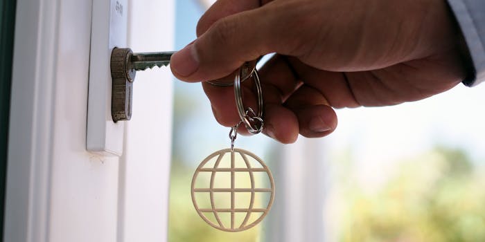 hand unlocks house using keychain of internet symbol