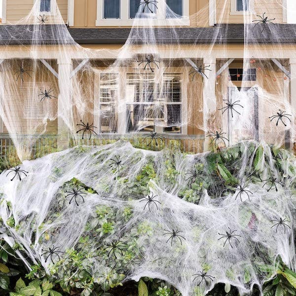 bush covered in fake spider webs and hundreds of fake spiders
