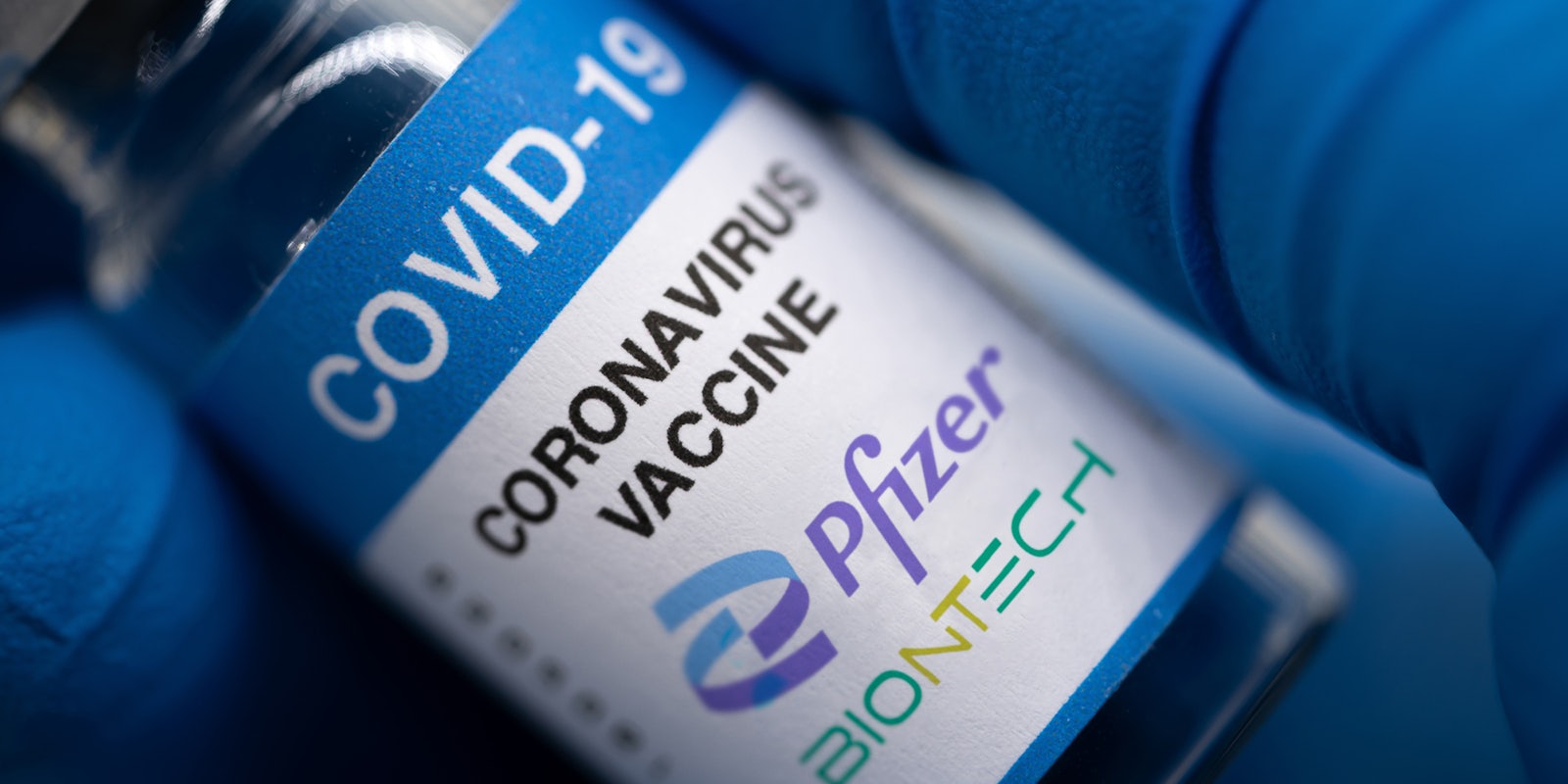 Covid-19 vaccine with Pfizer logo. Doctor's hand holds a bottle with a coronavirus vaccine on a white background.