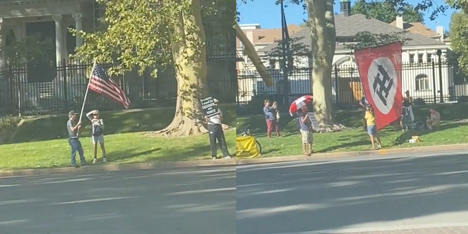 A Nazi flag is seen by the road alongside people protesting the COVID-19 vaccine