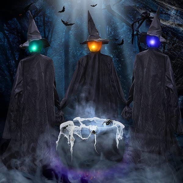 Three light up witches in black gowns and pointy hats gather around a bubbling caldron
