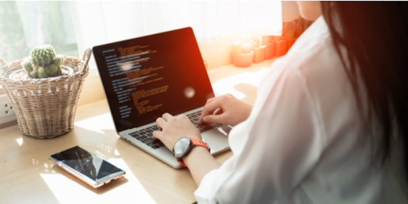 A woman codes javascript on a laptop