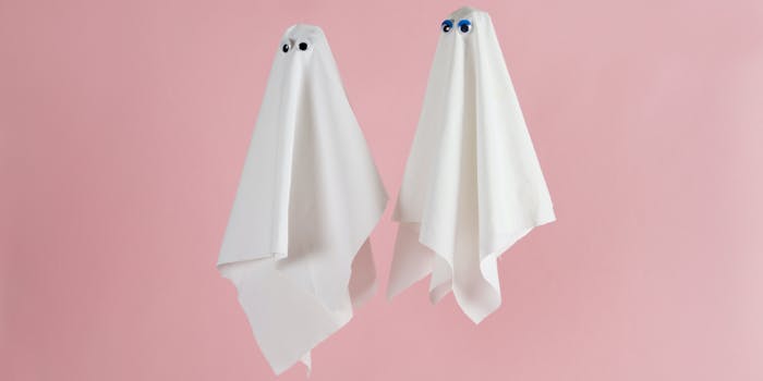 Couple of white sheet ghost with doll's eyes isolated on a pink background. Minimal pop still life photography