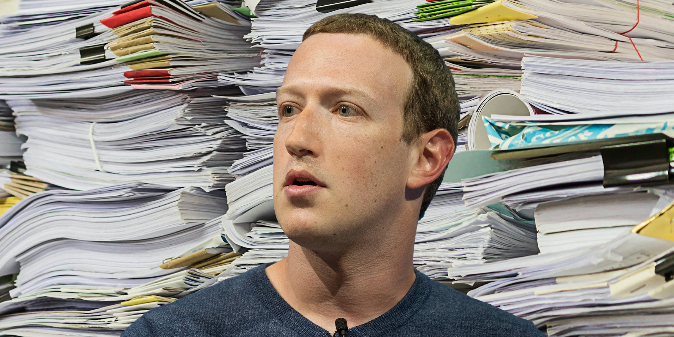 Mark Zuckerberg in front of a pile of memos, papers, and folders