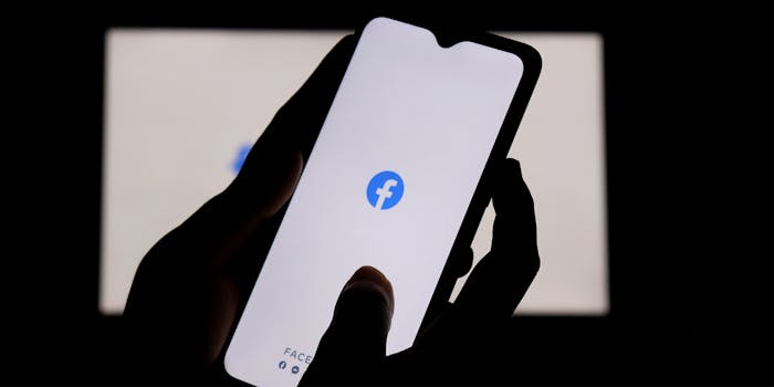 Hands holding phone with Facebook logo