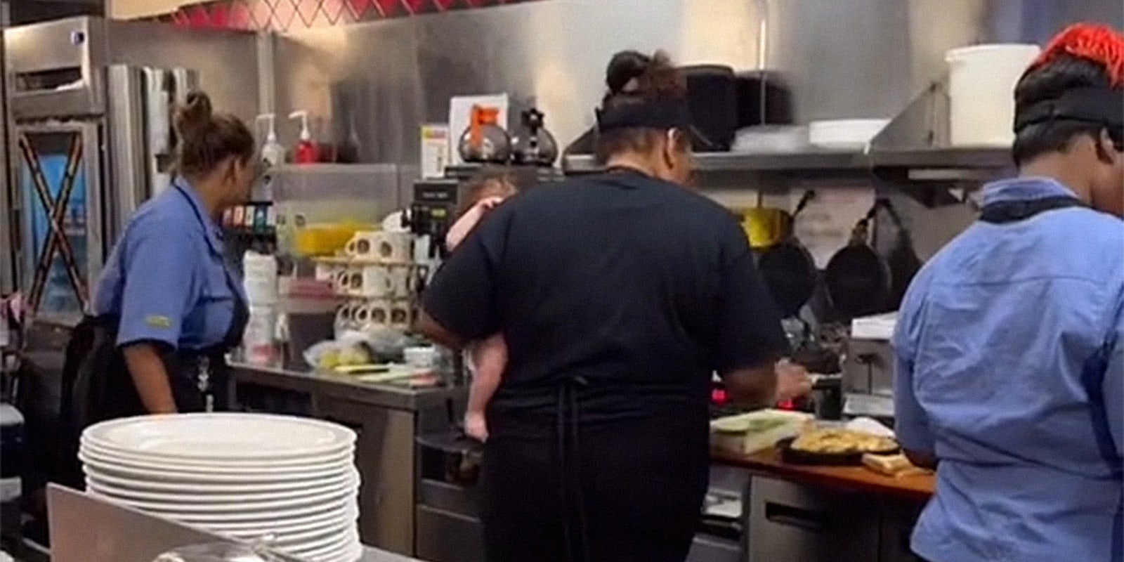 woman holding baby while she works in restaurant