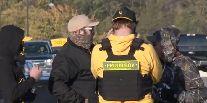 Man wearing rucksack with "Proud Boy" label with other men in parking lot