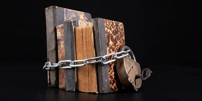 Old books strapping a shiny chain. Forbidden literature locked with a padlock. Dark background.