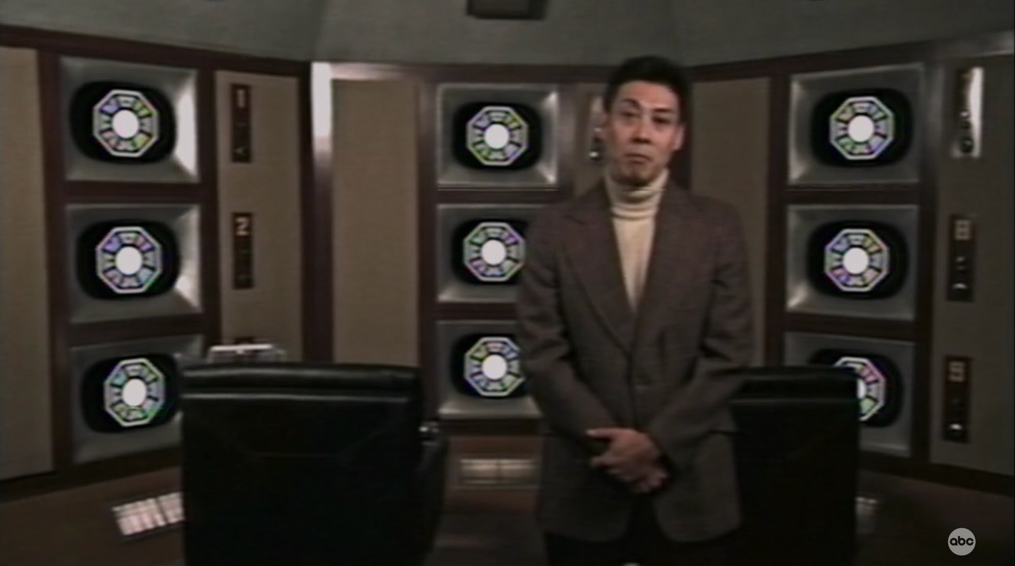 dr. mark wickmund standing in front of video screens in dharma orientation video