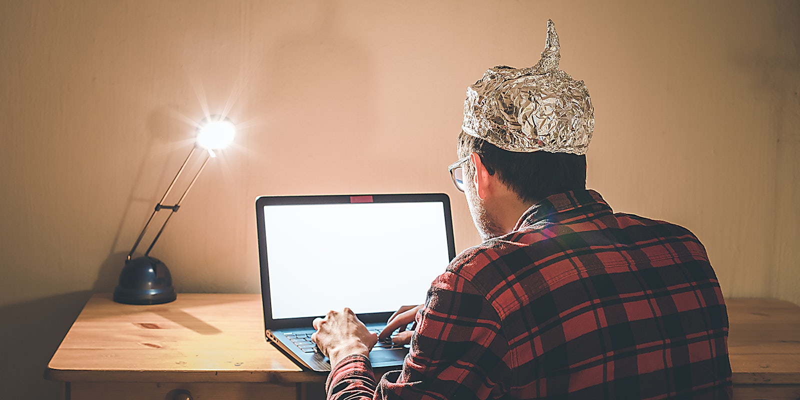 A man in an aluminum hat on a computer.