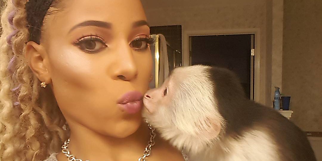 A woman kissing a monkey.