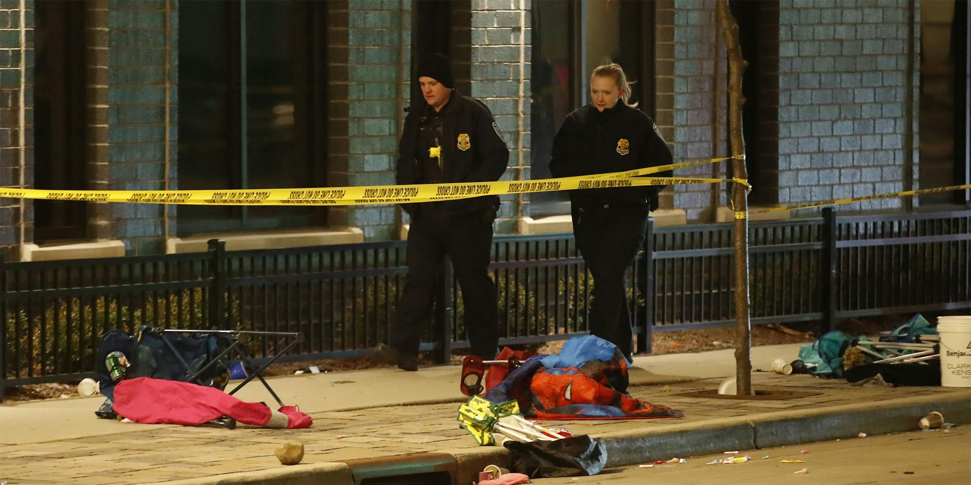 Police officers walk beside debris left from crowds attending a Christmas parade