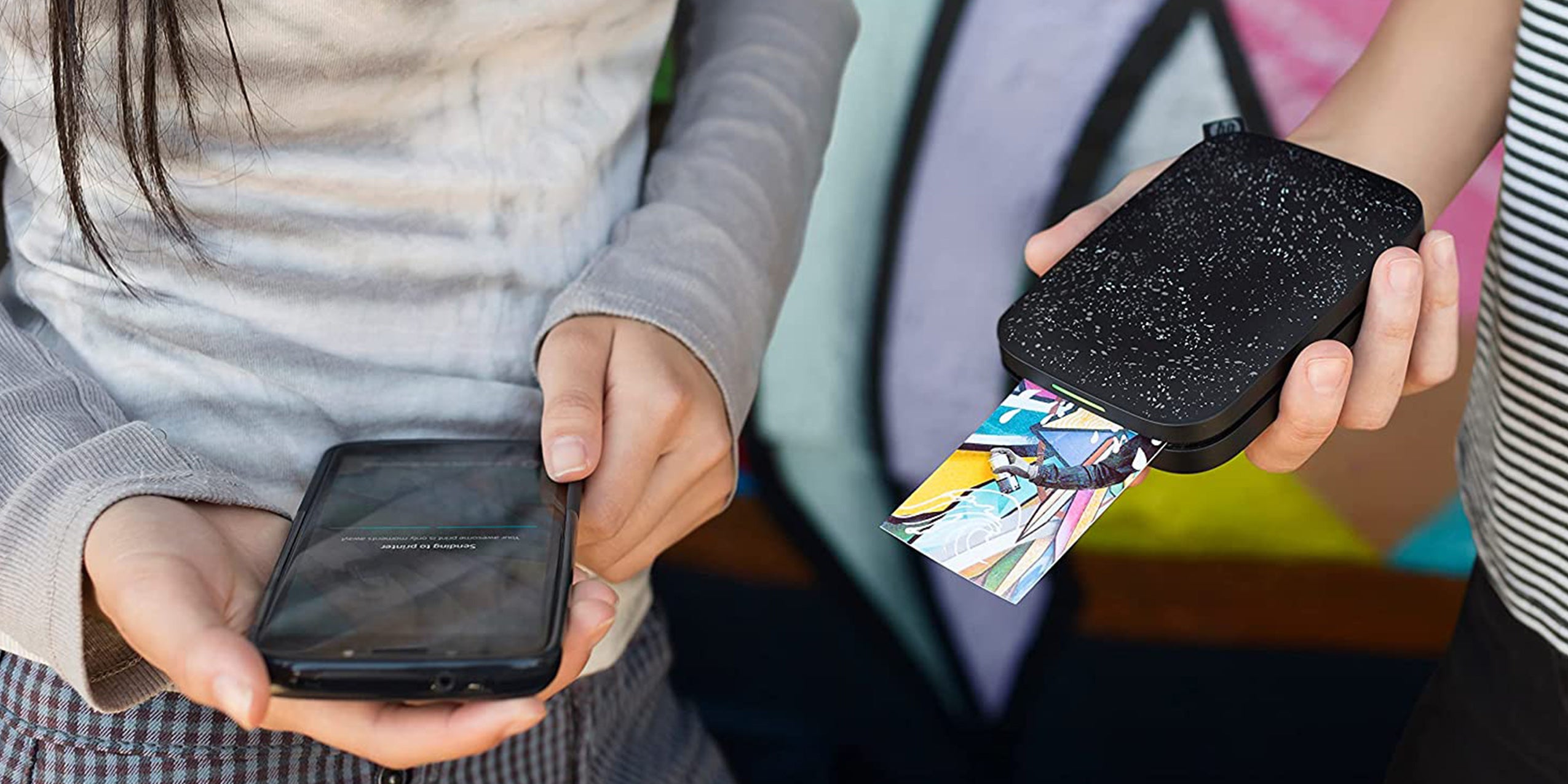 An HP Sprocket printer device being used by two women.