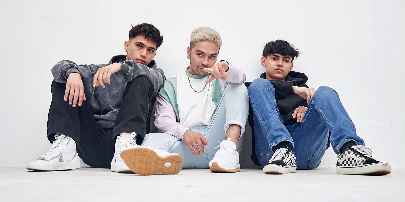 Three guys sitting on the floor and looking into camera.