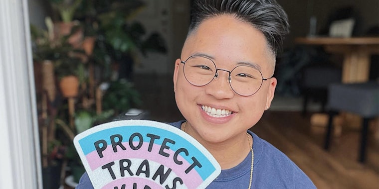 Person holding 'Protect Trans Kids' sticker