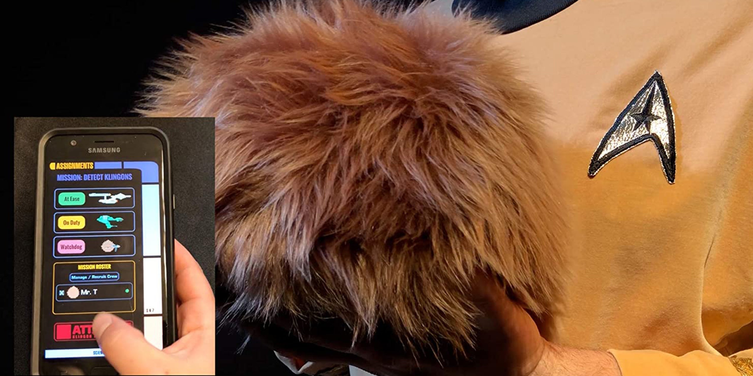 The Star Trek Tribble along with its companion app being held by someone wearing a gold Star Fleet uniform.