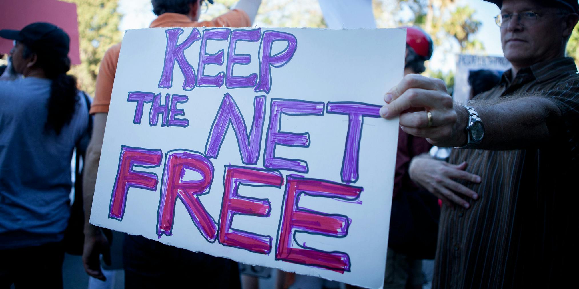 A person protesting in favor of net neutrality, holding a sign that says 'Keep the Net Free'