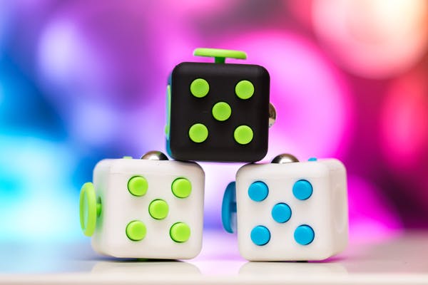 fidget cubes stacked in front of a brightly colored background