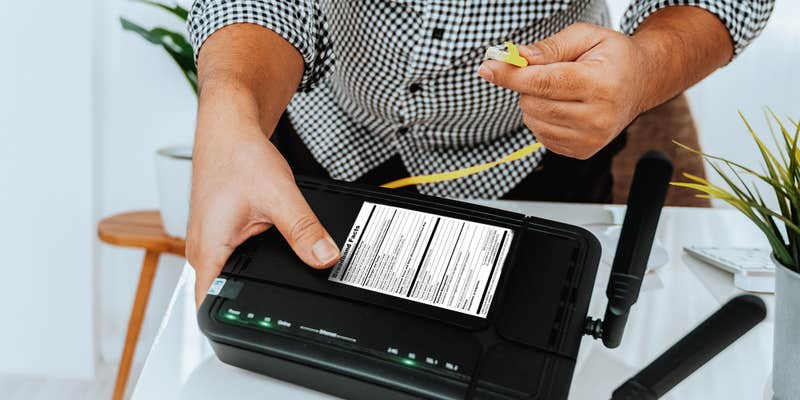 man holding router with Broadband Facts sticker on the top