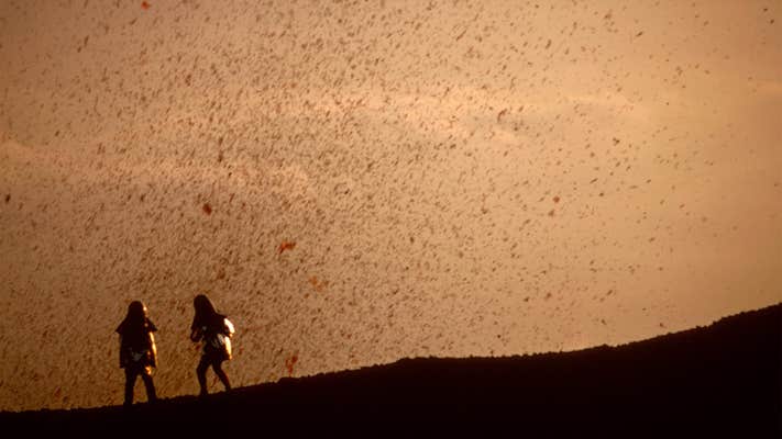 two people standing on a volcano in fire of love