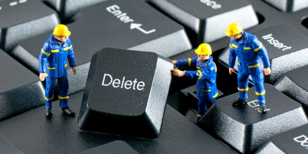 Team of construction workers working with DELETE button on a computer keyboard