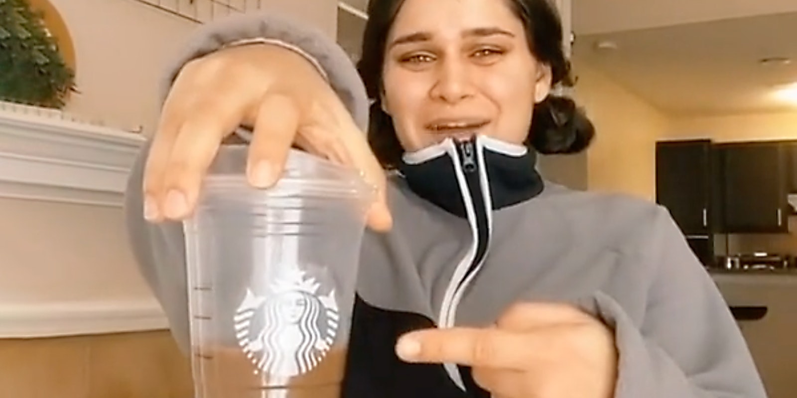A person pointing at a Starbucks cup.