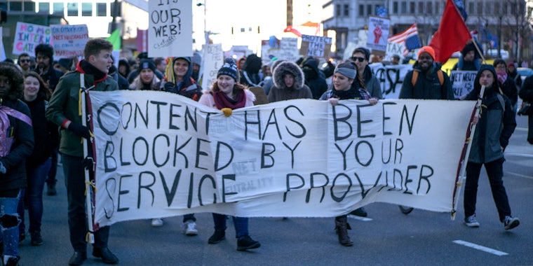 protesters hold sign that reads 'content has been blocked by your service provider'