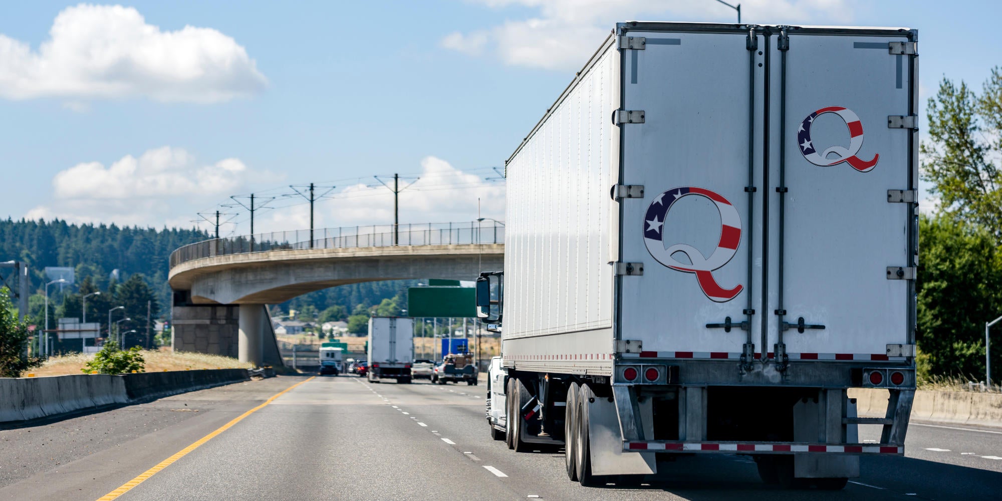 truck driving on road with Qanon stickers on the back