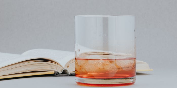Glass of irish whiskey with ice cubes next to an open book