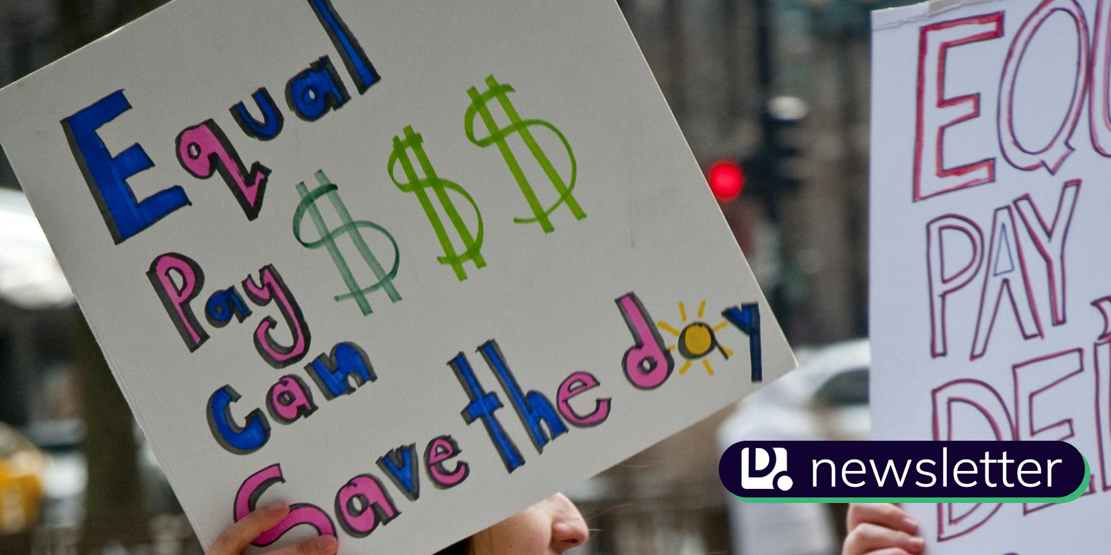 A sign that says 'Equal Pay Can Save The Day.' In the lower right corner, the Daily Dot newsletter logo can be seen.