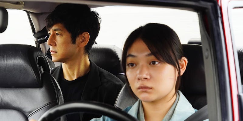 Drive My Car movie still showing a woman in the driver's seat with a man in the back