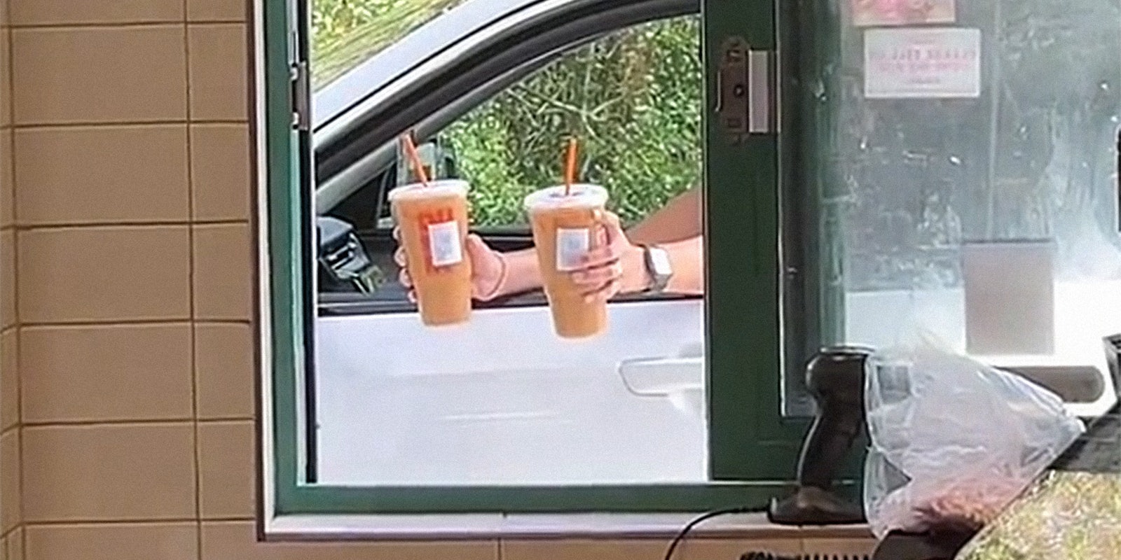 woman handing coffees back into drive-thru window