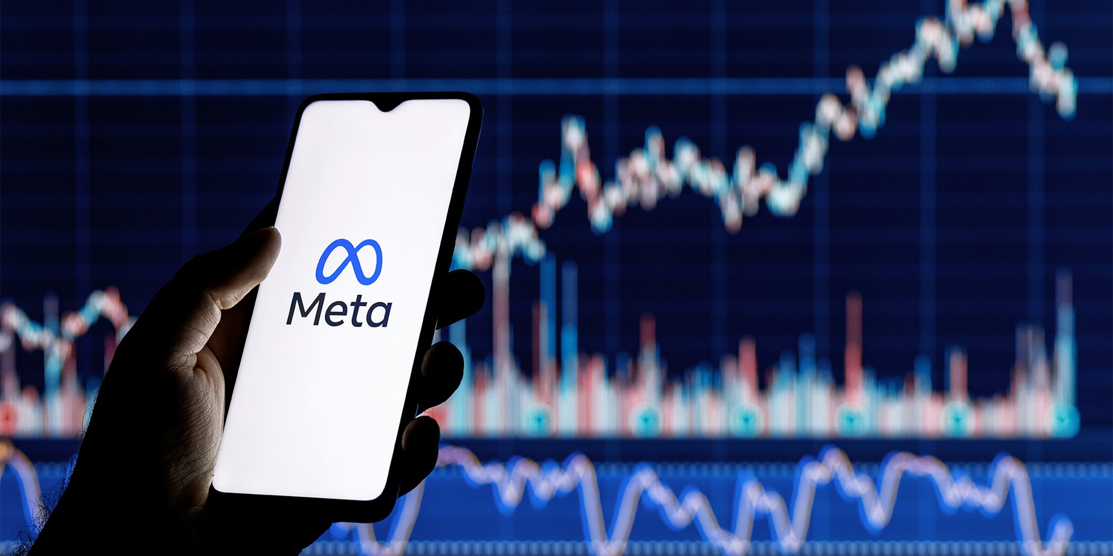 hand holding phone with Meta logo over stock tracker background