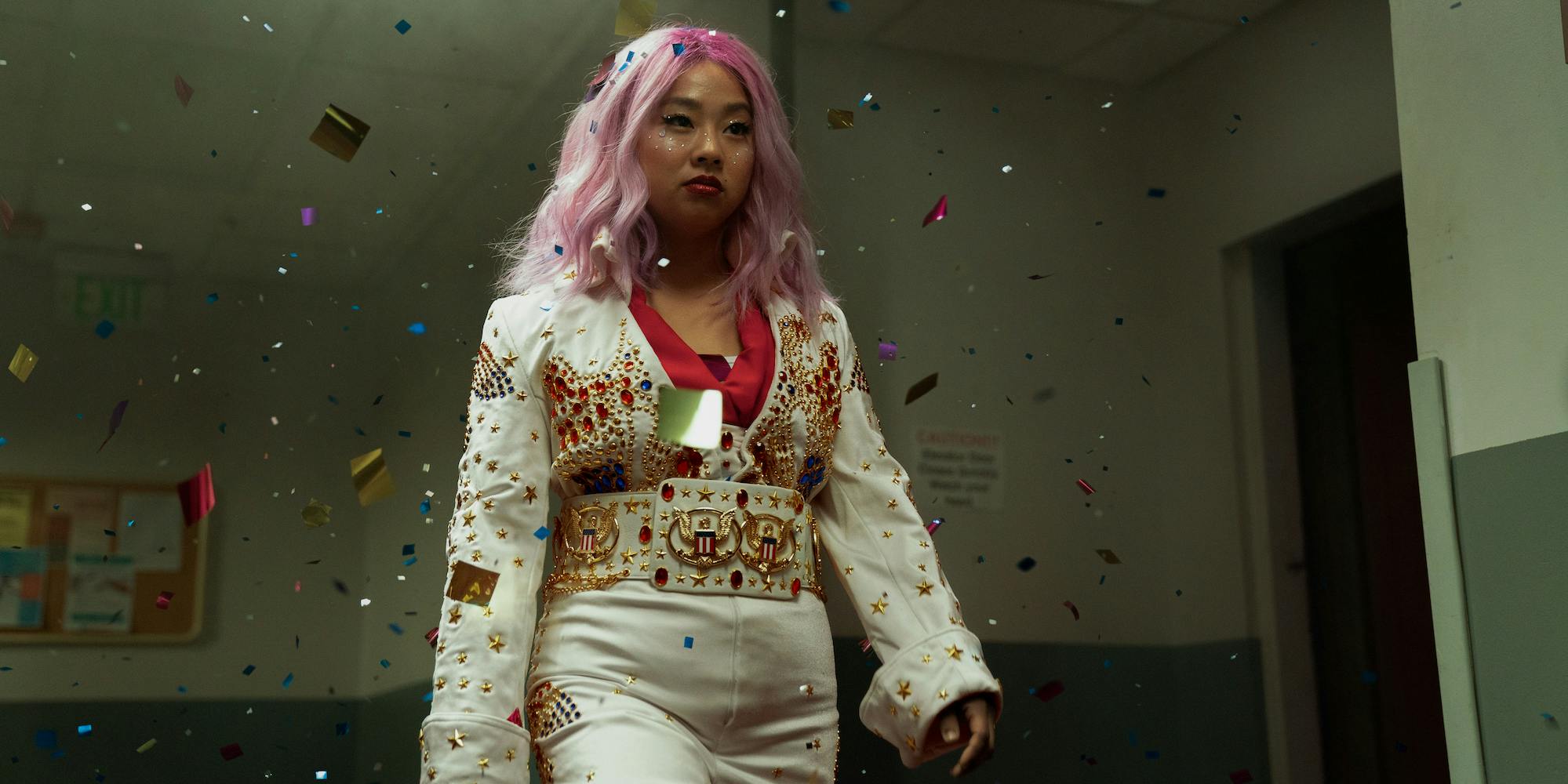 Stephanie Hsu dressed in a white suit decorated with stars and a belt, wearing a pink wig.