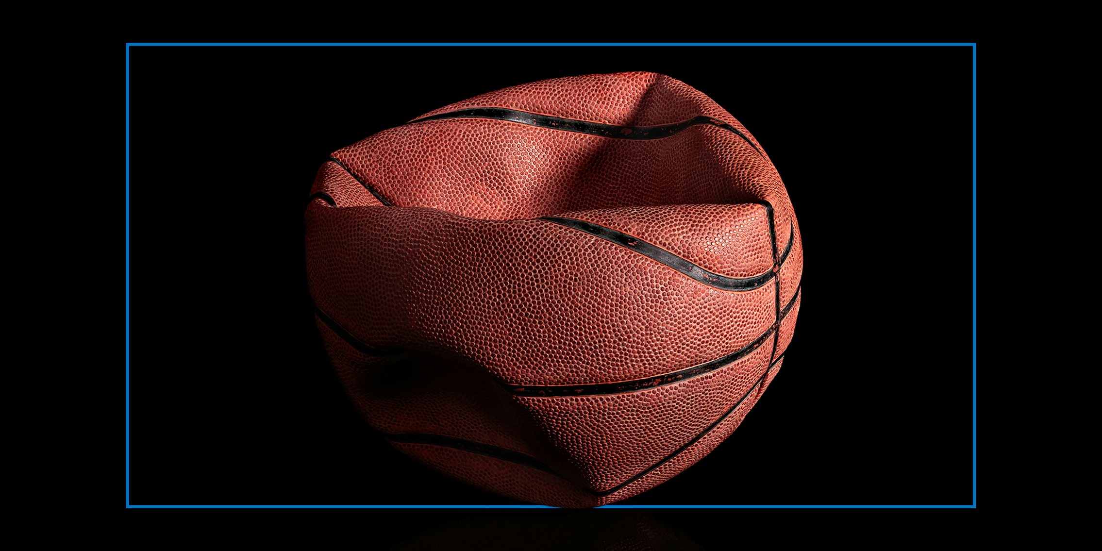 Deflated old basketball on black background. Reflection.