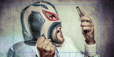 man in luchador mask reacting to phone in hand