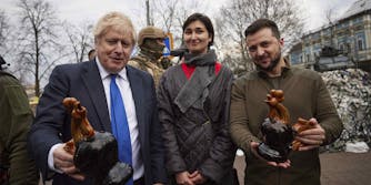 Ukrainian President Volodymyr Zelenskyy, right, and Britain's Prime Minister Boris Johnson pose for a picture with a woman, after she presented the gifts they hold, in Kyiv, Ukraine