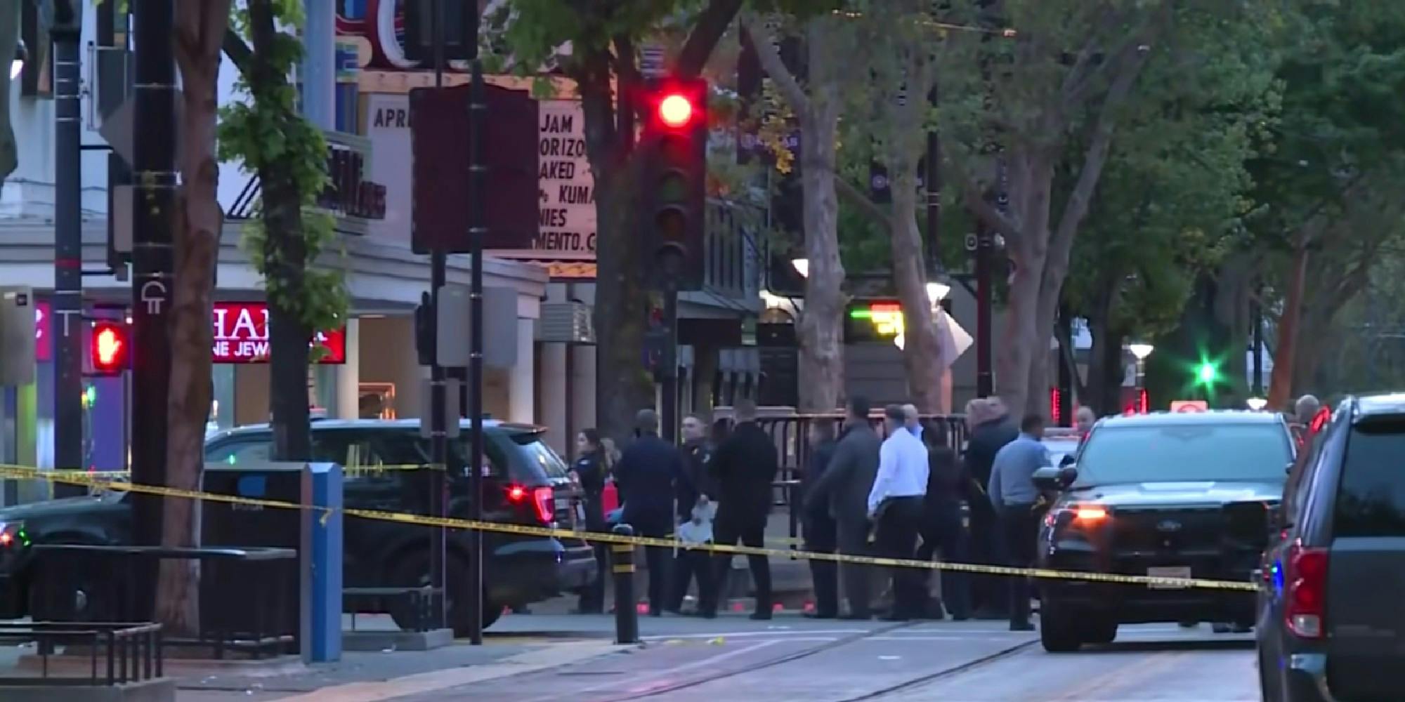 A crime scene on a city street with police vehicles and police officers