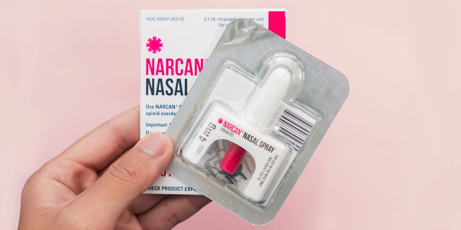 hand holding NARCAN NASAL SRAY on blush pink background