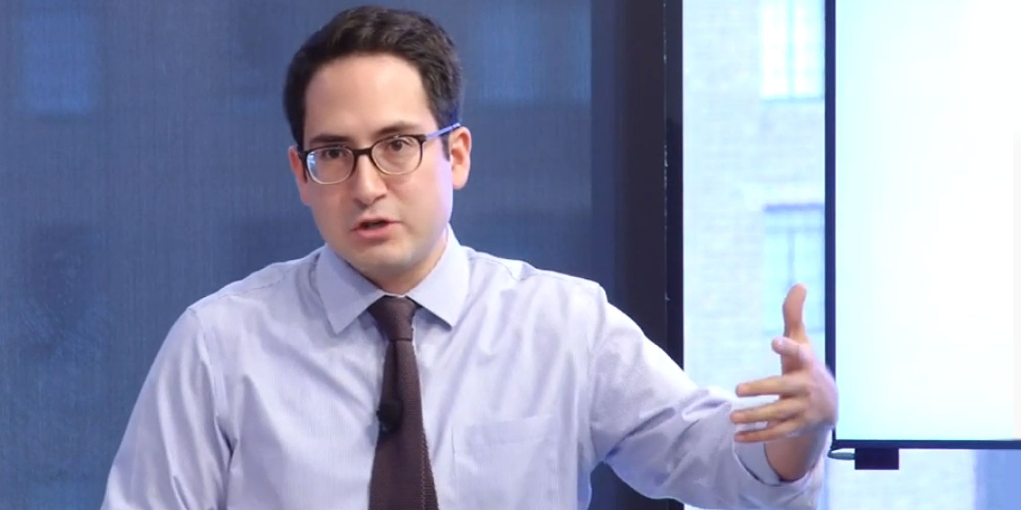 Alvaro Bedoya speaking hand up blue background